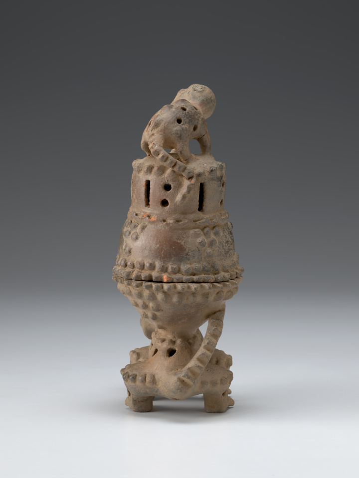 Escultura de cerámica de dos criaturas parecidas a los gatos, con un quemador de incienso en la espalda del animal más grande y un animal más pequeño de pie sobre la tapa.