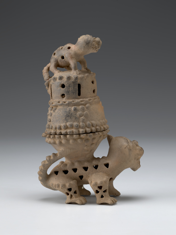 A ceramic sculpture of two cat-like creatures, with an incense burner on the larger animal’s back and a smaller animal standing on top of the lid.