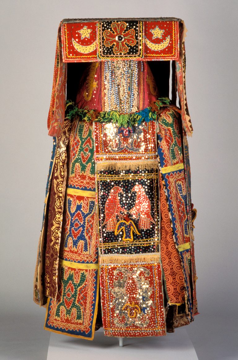 Full body costume made up of colorful layers of fabric, shells, sequins, and beads