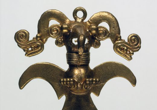 A gold pendant of an eagle wearing a headdress.