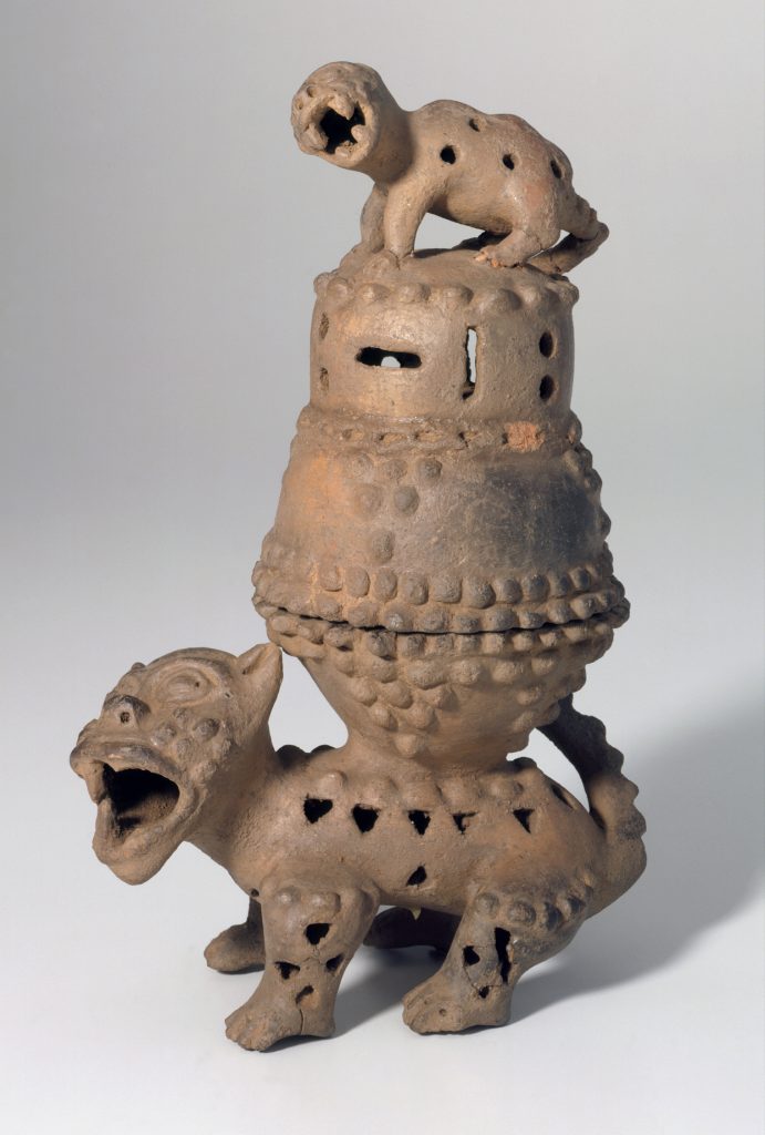 Escultura de cerámica de dos criaturas parecidas a los gatos, con un quemador de incienso en la espalda del animal más grande y un animal más pequeño de pie sobre la tapa.