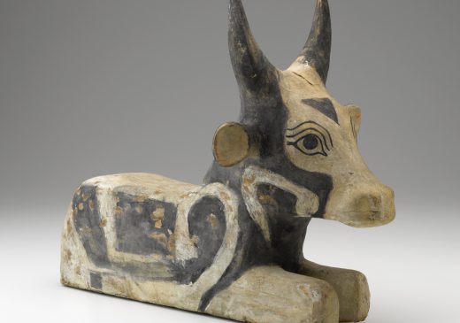 A wooden sculpture of a seated, black-and-white painted bull.