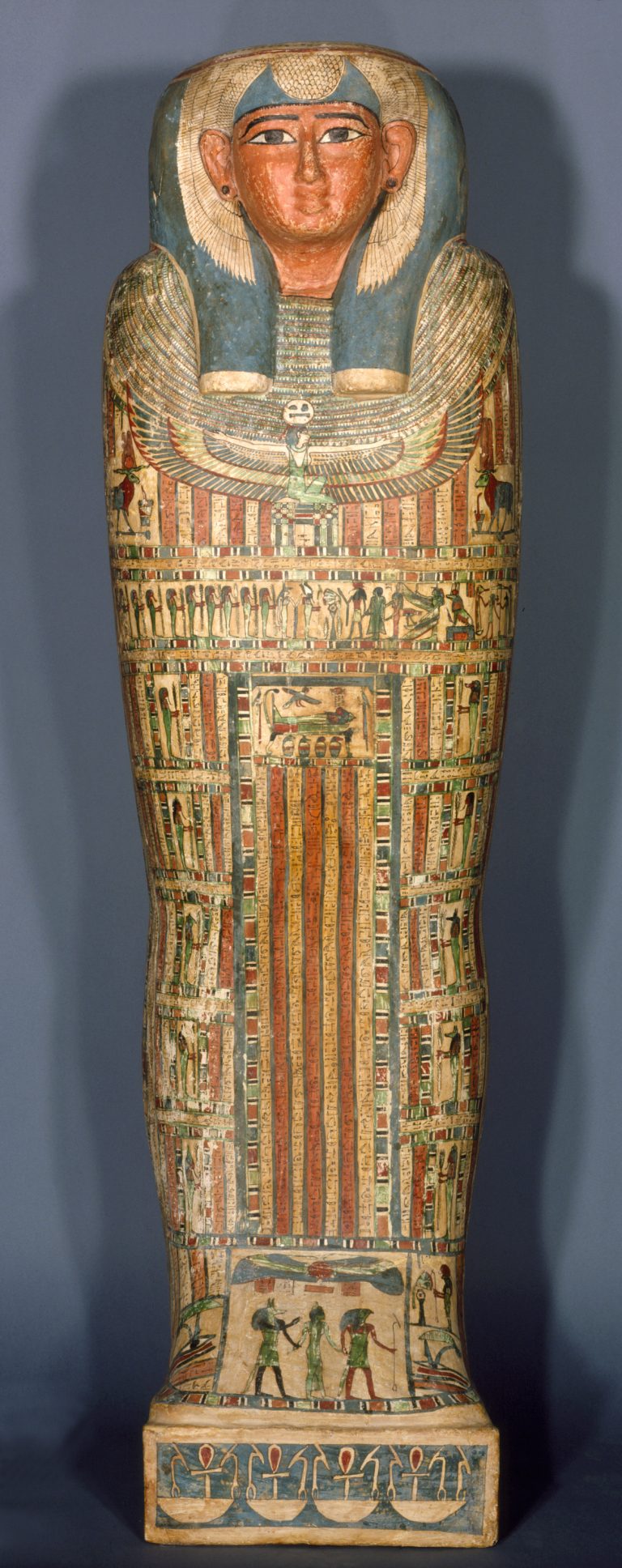A wooden coffin shaped like a human body, with ancient Egyptian symbols and deities painted on its surface.