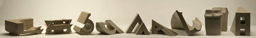 An image of nine three-dimensional cardboard sculptures of the letter A arranged in a line.