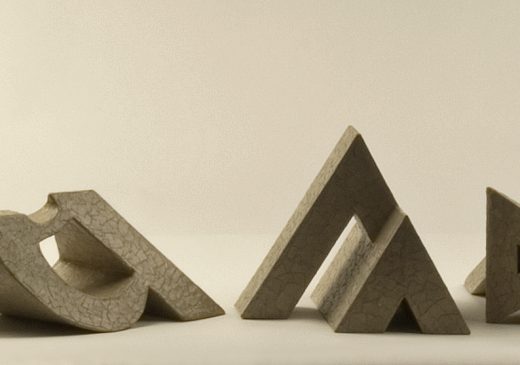 An image of nine three-dimensional cardboard sculptures of the letter A arranged in a line.