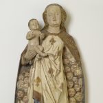 A wooden sculpture depicting the Virgin Mary holding the Christ child, who is bestowing a blessing on the viewer. Under her cloak Mary shelters dozens of faithful believers.