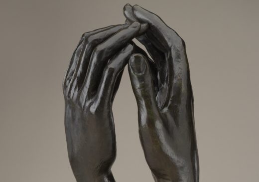 A bronze sculpture of two right hands reaching toward one another, with the fingertips just touching.