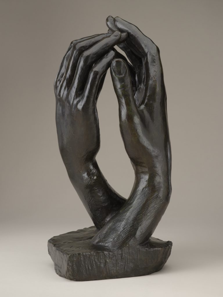 Bronze sculpture of two right hands facing each other with fingertips touching.