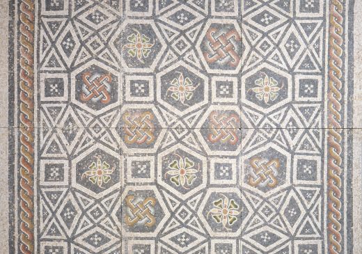 A Roman mosaic featuring floral and geometric patterns made with pieces of white marble and colored glass.
