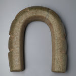 Bottom view of a carved u-shaped stone yoke resembling a frog.