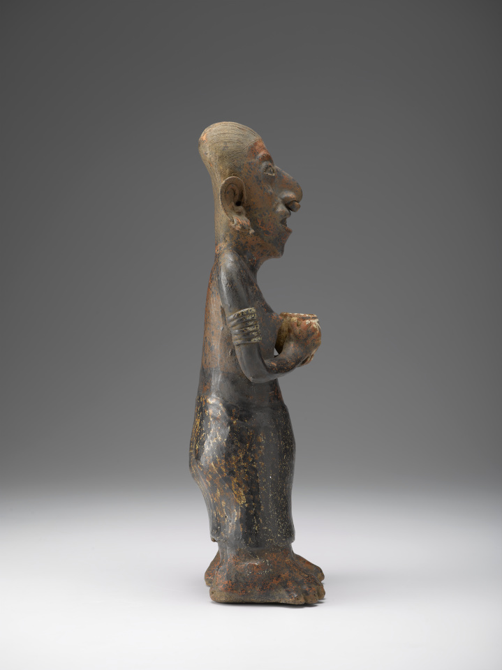 A ceramic figure of a woman holding a cup and wearing jewelry and a skirt.