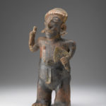A ceramic figure of a man holding a blade in one hand and a bird-like item in the other.
