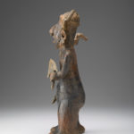 A ceramic figure of a man holding a blade in one hand and a bird-like item in the other.