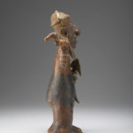 A ceramic figure of a man holding a blade in one hand and a bird-like item in the other.