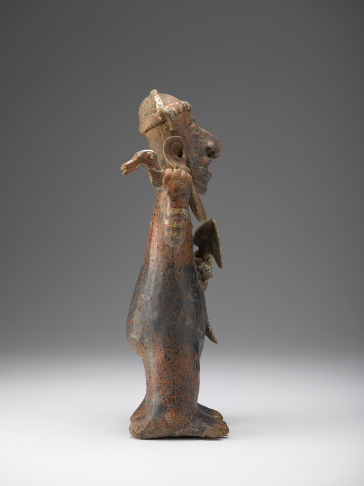 A ceramic figure of a man holding a blade in one hand and a bird-like item in the other.