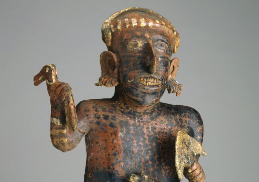 Figura de cerámica de un hombre que sostiene una espada en una mano y un objeto parecido a un pájaro en la otra.