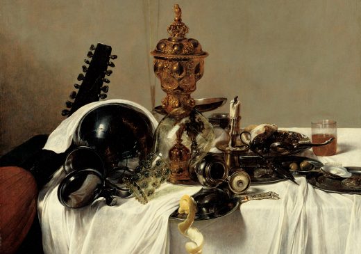 An oil painting of a table with a white tablecloth in front of a plain wall. The table is scattered with food and drinks. Two containers, made of pewter and glass, are overturned near the edge of the table. A gold centerpiece and a tall flute glass tower over the objects in the center of the painting. The neck of a lute leans against the table.