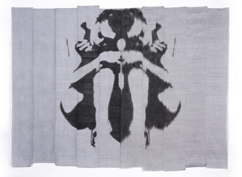A piece of gray cloth with an almost symmetrical black inkblot design in the middle.