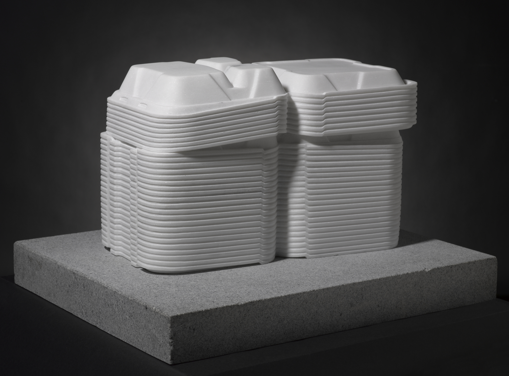 OAKLEY, Stack, 2012_10, view B A white marble sculpture of open Styrofoam takeout boxes stacked on top of a gray, rectangle-shaped base.