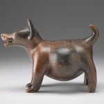 Side view of a brown and red ceramic sculpture shaped like a dog.