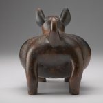 Rear view of a brown and red ceramic sculpture shaped like a dog.