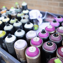 an array of spray paints used as materials for a mural