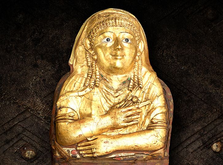 Se muestra una momia dorada que cubre desde la cabeza hasta el torso con los brazos cruzados en la cintura