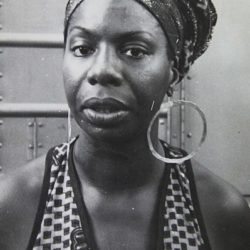 black and white photo of Nina Simone in a sleeveless top and hoop earrings