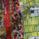 Detail view of large mixed media sculpture made of multicolored, interconnected metal pieces.