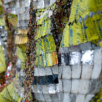 Detail view of large mixed media sculpture made of multicolored, interconnected metal pieces.