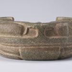 Front view of a carved u-shaped stone yoke resembling a frog.