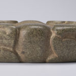 Side view of a carved u-shaped stone yoke resembling a frog.