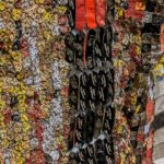 Detail view of large mixed media sculpture made of multicolored, interconnected metal pieces.
