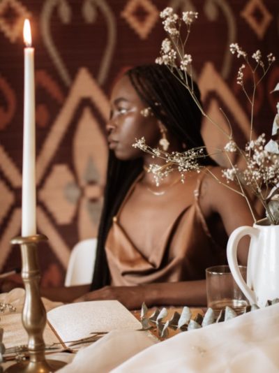 Retrato de perfil de una joven negra sentada detrás de una mesa decorada