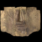 Back of gold metal mask with three seams visible. Indentations for the nose and mouth are at the center with round earpieces on each side.