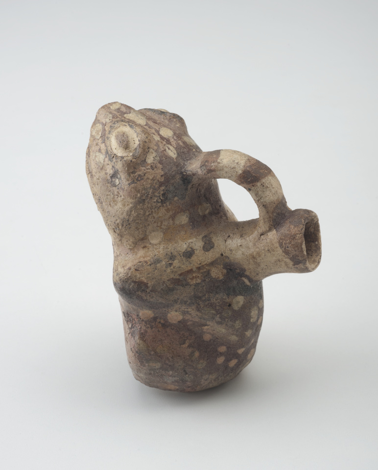 Recipiente de cerámica con forma de rana, con un asa que conecta la parte superior de la cabeza de la rana con un pico en su espalda.