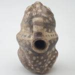 Rear view of a ceramic vessel shaped like a frog with a circular spout.