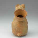 Rear view of a ceramic vessel shaped like a hairless dog. A circular opening to the spout is visible.
