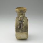 A ceramic vessel featuring a pair of monkeys with their hands covering their mouths. Their tails curve upward and connect with the neck of the vessel, serving as handles.