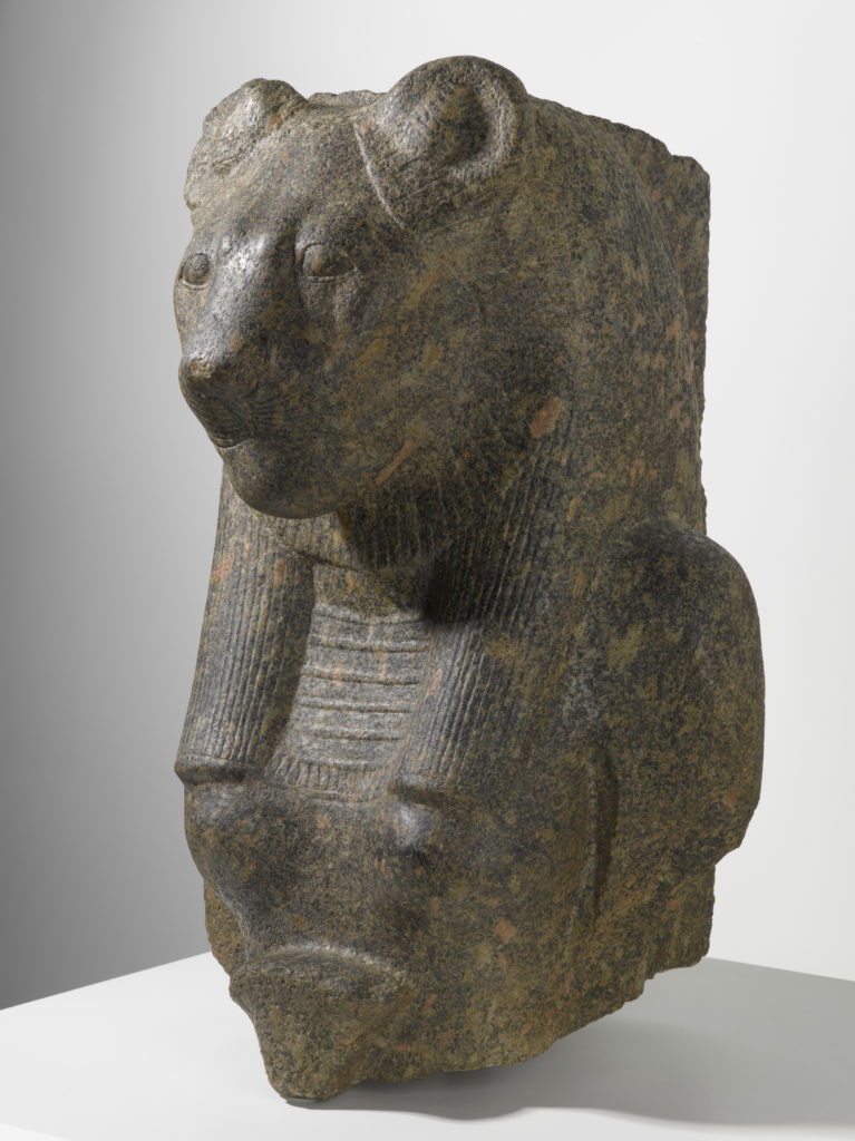 Escultura de granito con la parte superior del torso, el pecho y los hombros de una mujer y la cabeza de una leona.