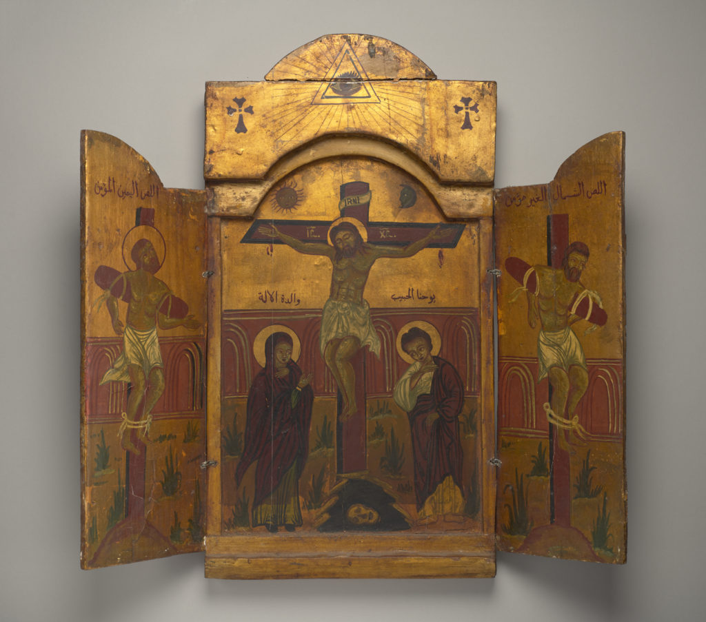 The triptych's two doors open to reveal a three-panel painting of Christ’s crucifixion, featuring Arabic text and Egyptian iconography.