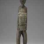 A small wooden sculpture of a woman with most of her torso covered by a burlap cloth. Front view.