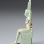 A small sculpture of the Egyptian goddess Isis with remnants of the infant body of Horus. Side view.