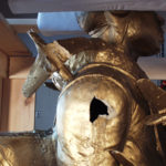 Detail of the right shoulder showing damage: broken airplane at upper left and hole in the arm where another airplane once was attached.