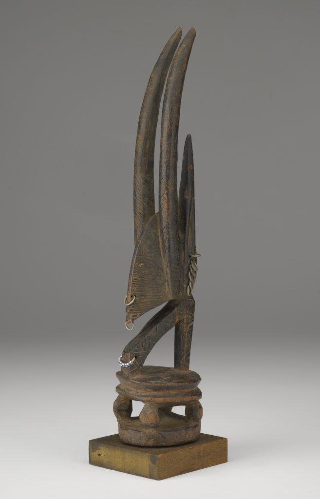 A wooden sculpture shaped like an antelope’s head with tall, narrow horns.