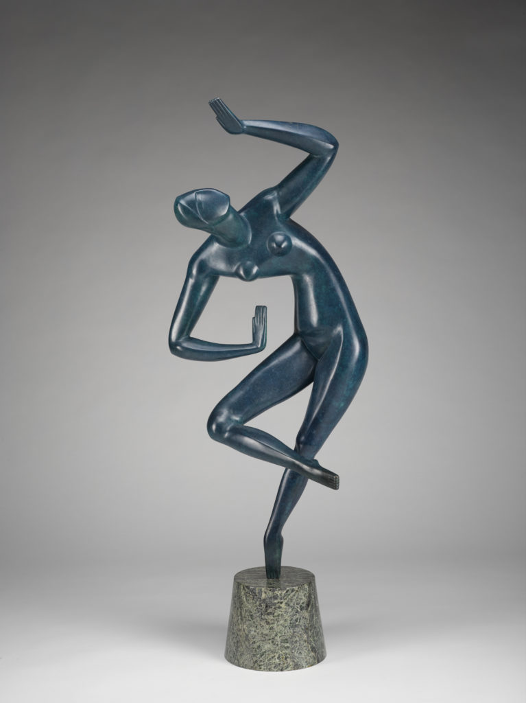 A sculpture of a blue human figure on a small stone pedestal against a gray background. The figure is standing on one leg, with the other leg bent. Its upper body is leaning to the side, with one arm bent above its head and the other arm bent at its waist. Front view.