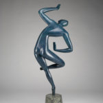 A sculpture of a blue human figure on a small stone pedestal against a gray background. The figure is standing on one leg, with the other leg bent. Its upper body is leaning to the side, with one arm bent above its head and the other arm bent at its waist. Reverse view.