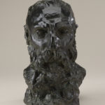 A bronze sculpture of the head, neck, and upper shoulders of a bearded man. Front view.