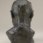 A bronze sculpture of the head, neck, and upper shoulders of a bearded man. View of reverse.