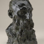 A bronze sculpture of the head, neck, and upper shoulders of a bearded man. Alternate view.